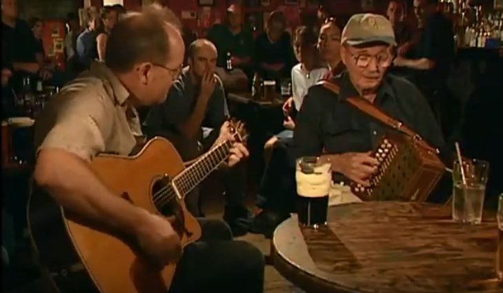 A Man playing an accordion with a guitar player in a pub in Ireland