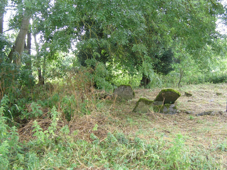 A Country churchyard showing head stones falling over with over grown grass and trees
