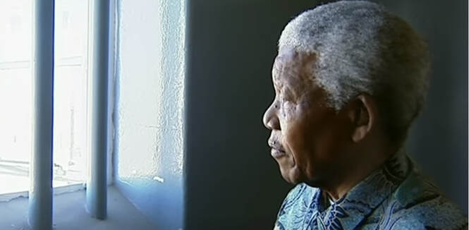 The Legend Nelson Mandela inside prison cell looking out the window that has bars