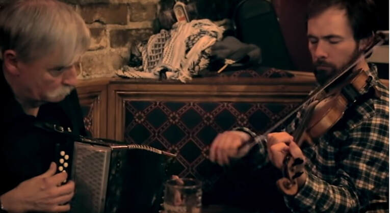 A Man playing a fiddle in an Irish pub