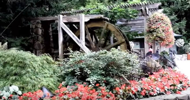 Gardens of the rich showing water wheel and summer flowering plants in raised beds