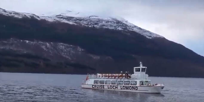 Cruse boat on Loch Lomond with mountains in the background