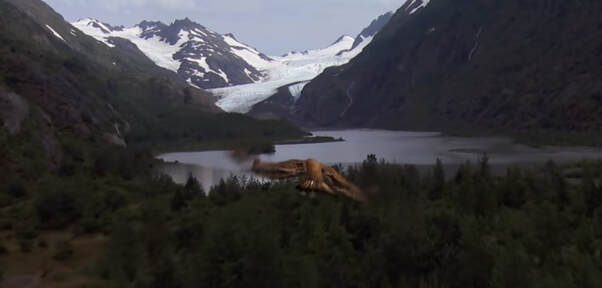 Snowy mountains in the background with lake in the middle and small shrubs in the forground