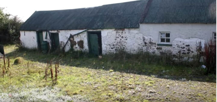 Old farm house with sheds and tin roof with white washed walls and yard