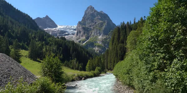 River flowing through a valley with mountain and trees in the background